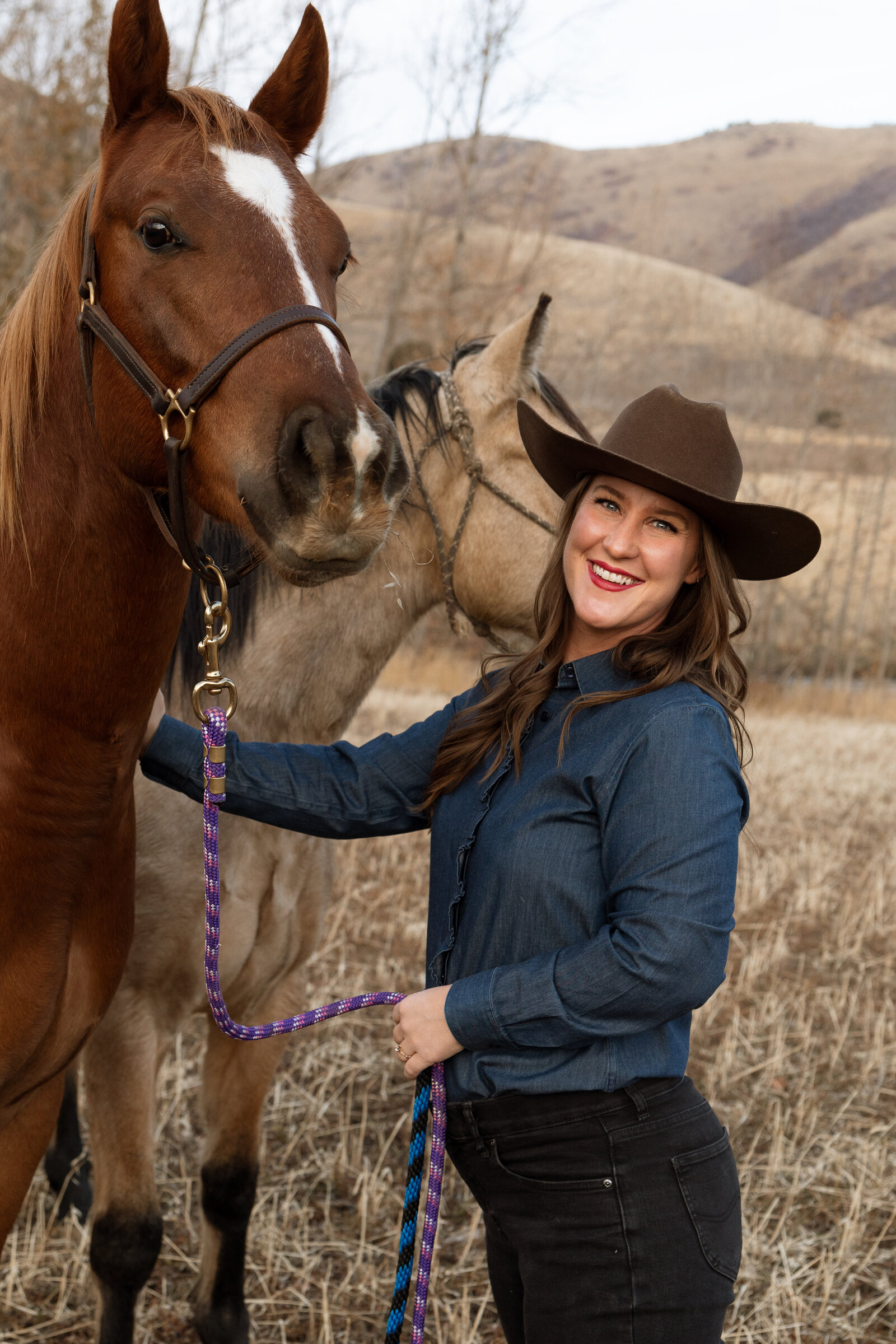 Nicole Burnett smiling beside her horse, wearing a western hat